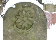 Blumensymbol auf einem Grabmal in Sandstein gehauen.