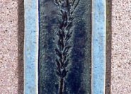 Eine moderne Symboldarstellung: Das Symbol ist aus Keramik hergestellt und bringt mit seiner blauen Glasur Farbe in die Grabmalgestaltung.  In dieser zurückhaltenden Ausführung ist farbige Grabmalgestaltung zu begrüßen.