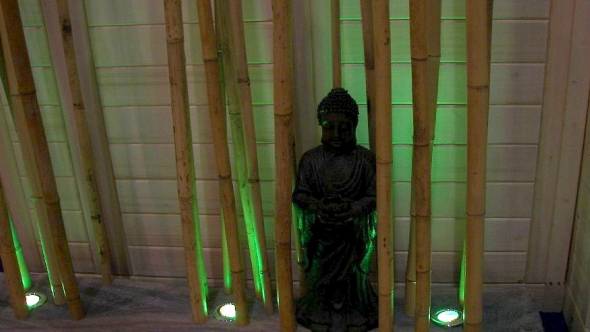 Buddafigur, Bambusrohr und Lichtdesign mit Bodenstrahlern